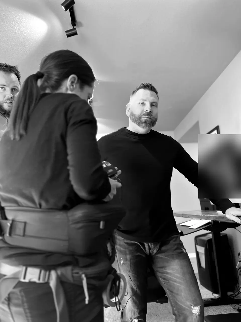 Behind the scenes filming for A&E’s Accused: Guilty or Innocent? (John Lott case): Craig Smith standing in his office with the camerawoman in the foreground and a man at the left edge; monitor obscured