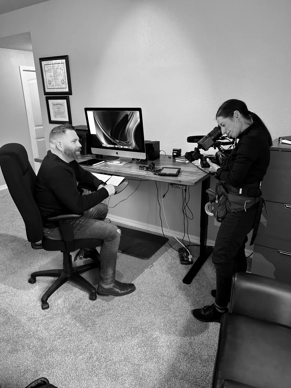 Behind the scenes filming for A&E’s Accused: Guilty or Innocent? (John Lott case): Craig Smith seated at his desk while the camerawoman films