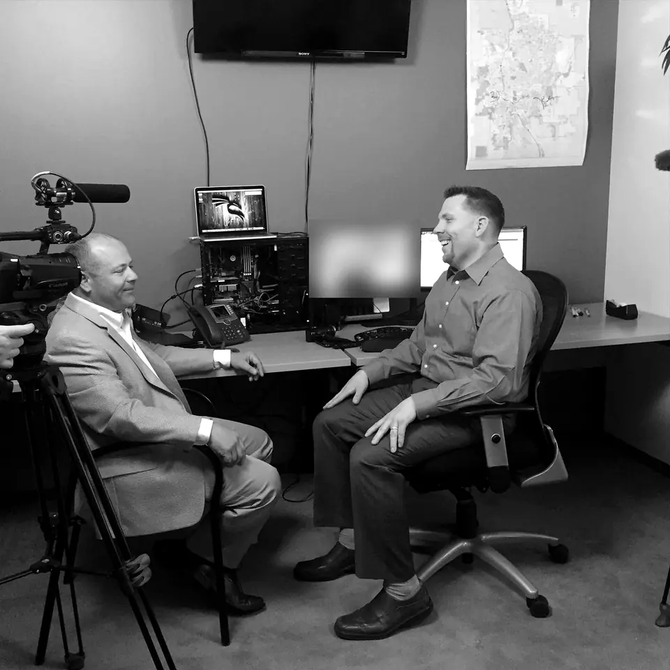 Craig Smith being interviewed for a television show in an office; screen content obscured
